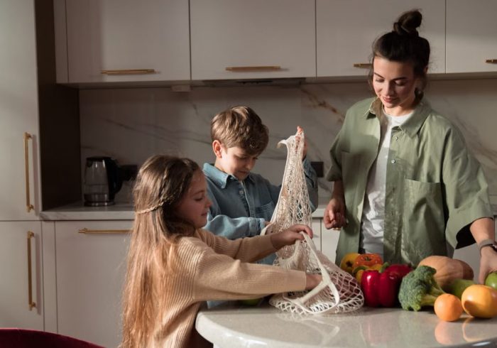 A happy family of three enjoying quality time unpacking vegetables in a modern kitchen.